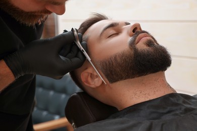 Photo of Professional hairdresser working with client in barbershop, closeup