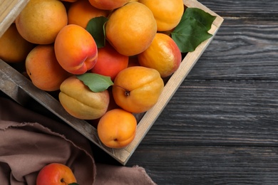 Many fresh ripe apricots on black wooden table, flat lay