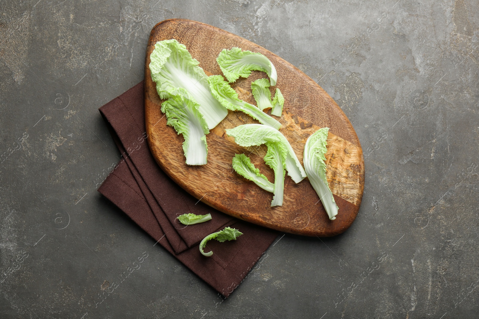 Photo of Pieces of fresh Chinese cabbage on gray textured table, top view