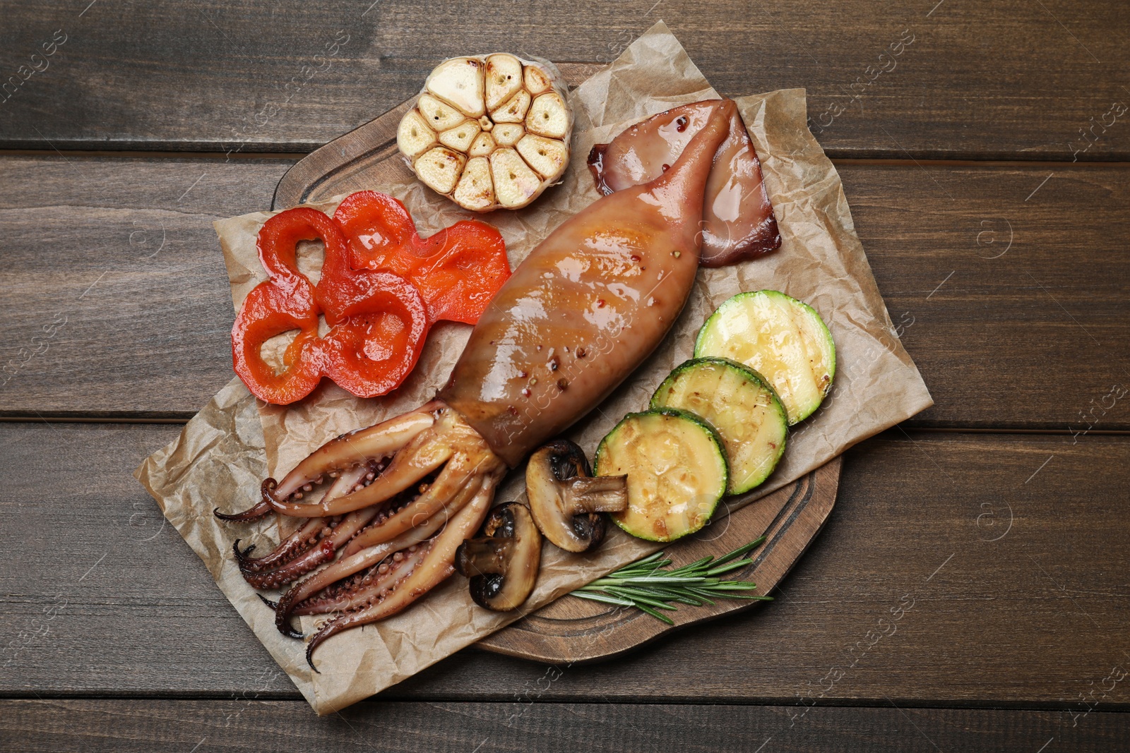 Photo of Tasty grilled squid served on wooden table, top view