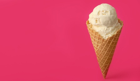 Photo of Delicious ice cream in waffle cone on pink background. Space for text