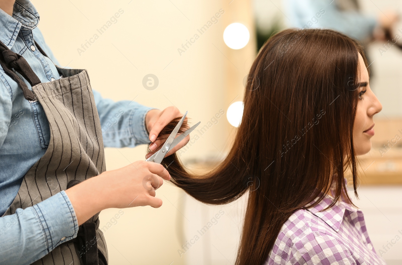 Photo of Barber making stylish haircut with professional scissors in beauty salon