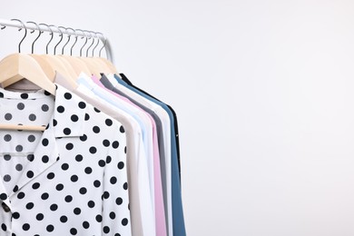 Dry-cleaning service. Many different clothes hanging on rack against white background, space for text