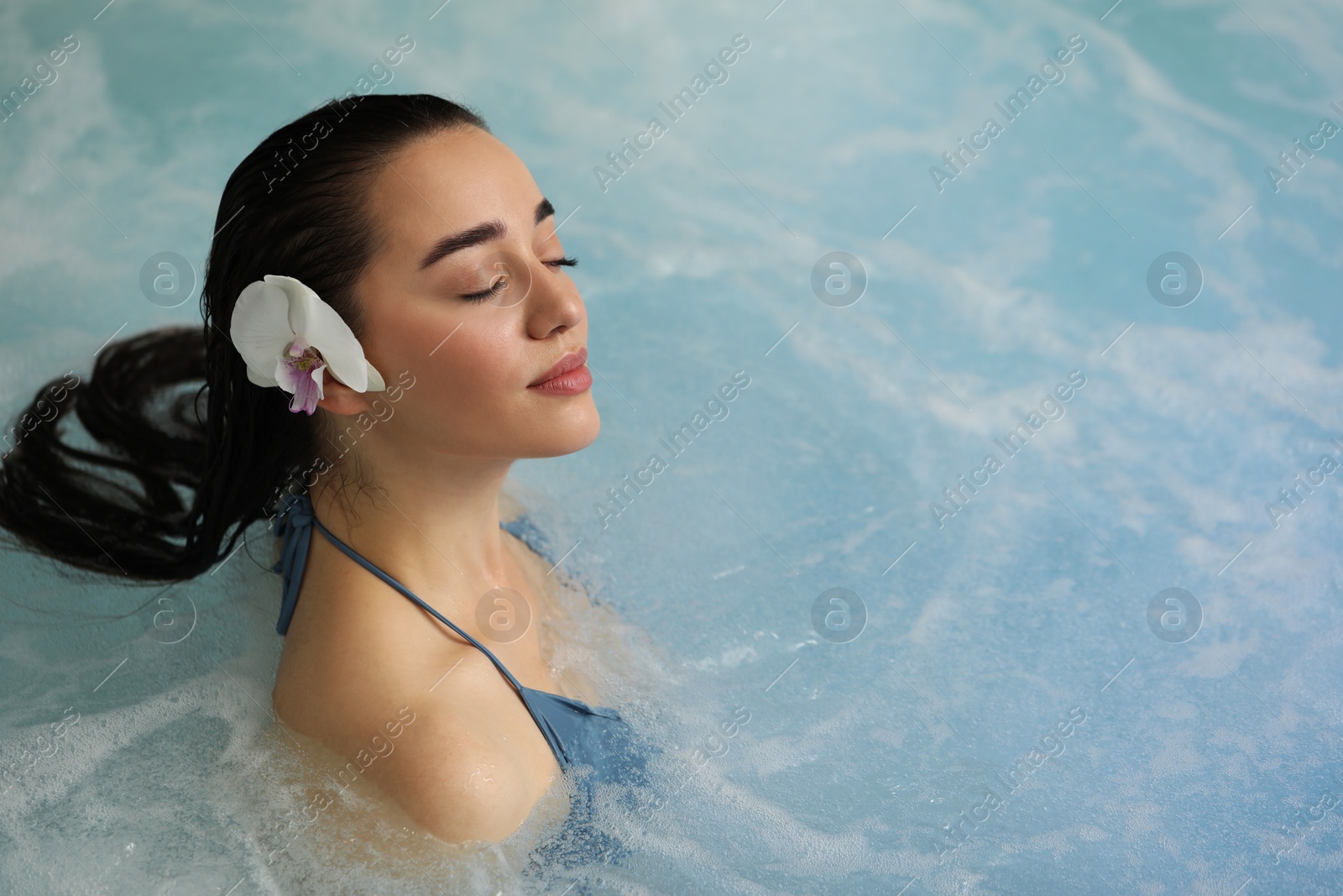 Photo of Beautiful woman with orchid flower in spa swimming pool, space for text