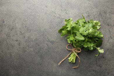 Photo of Bunch of fresh coriander on gray textured table, top view. Space for text