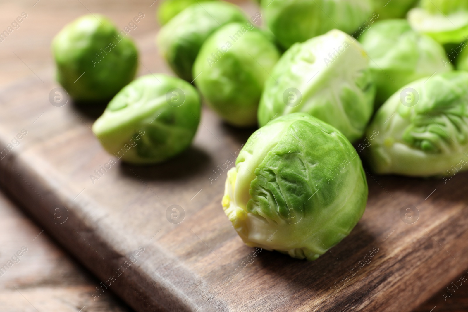 Photo of Wooden board with Brussels sprouts on table, closeup