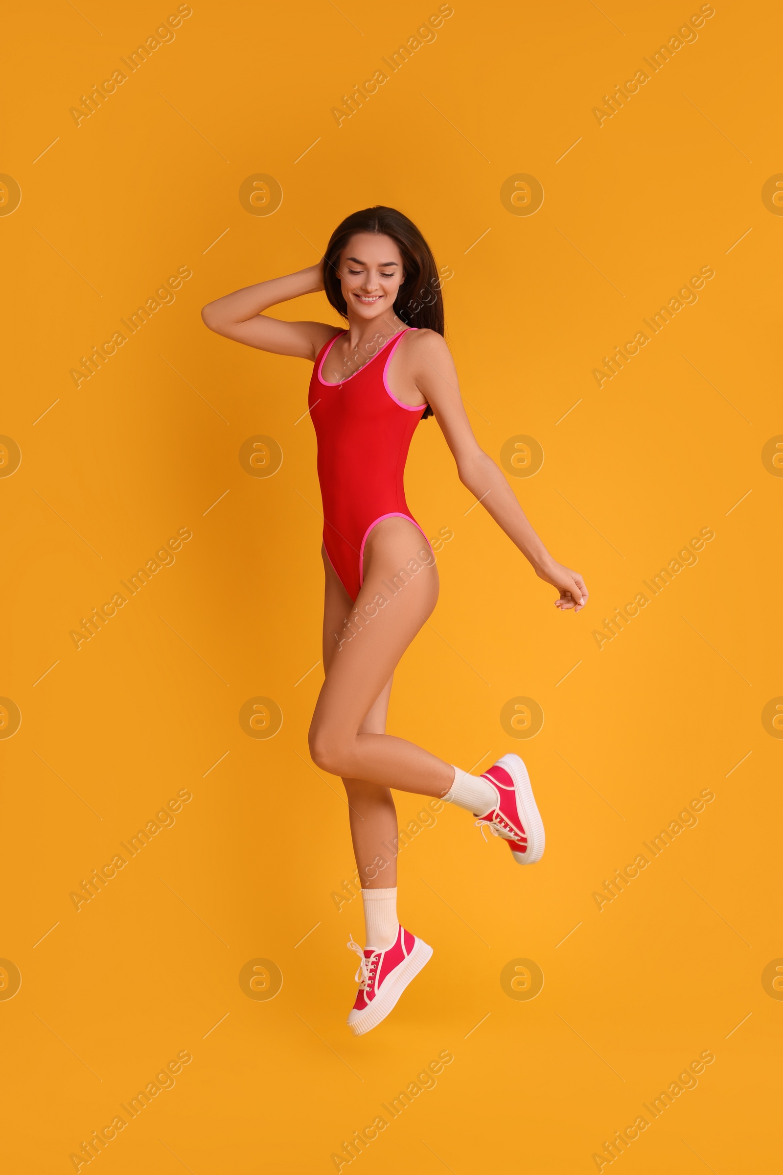 Photo of Young woman in stylish swimsuit on yellow background