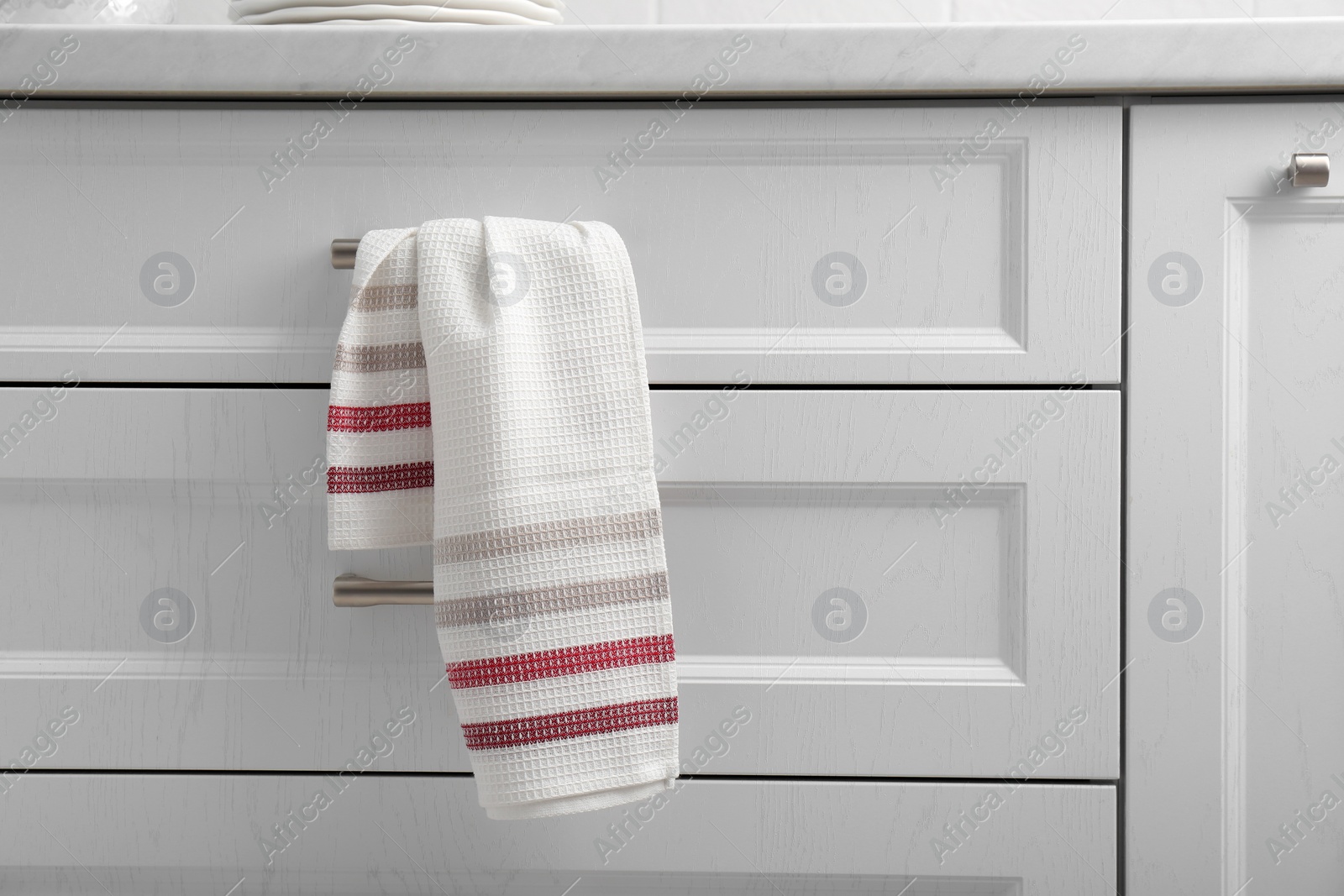 Photo of Soft kitchen towel hanging on drawer handle indoors
