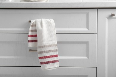 Photo of Soft kitchen towel hanging on drawer handle indoors