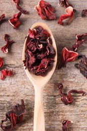 Spoon with dry hibiscus tea on wooden table, flat lay