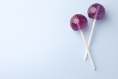 Tasty lollipops on light blue background, flat lay. Space for text