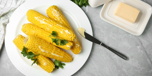 Image of Tasty boiled corn cobs served on light grey marble table. Banner design