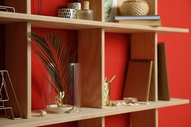 Photo of Stylish wooden shelves with decorative elements on red wall