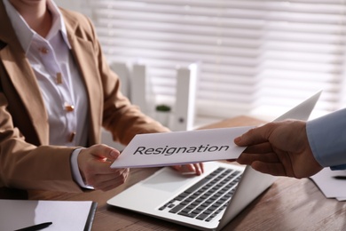 Photo of Employee giving resignation letter to boss in office, closeup