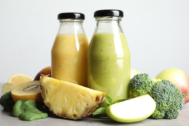 Bottles of delicious juices and fresh fruits on grey table