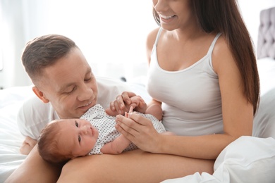 Photo of Happy couple with their newborn baby on bed