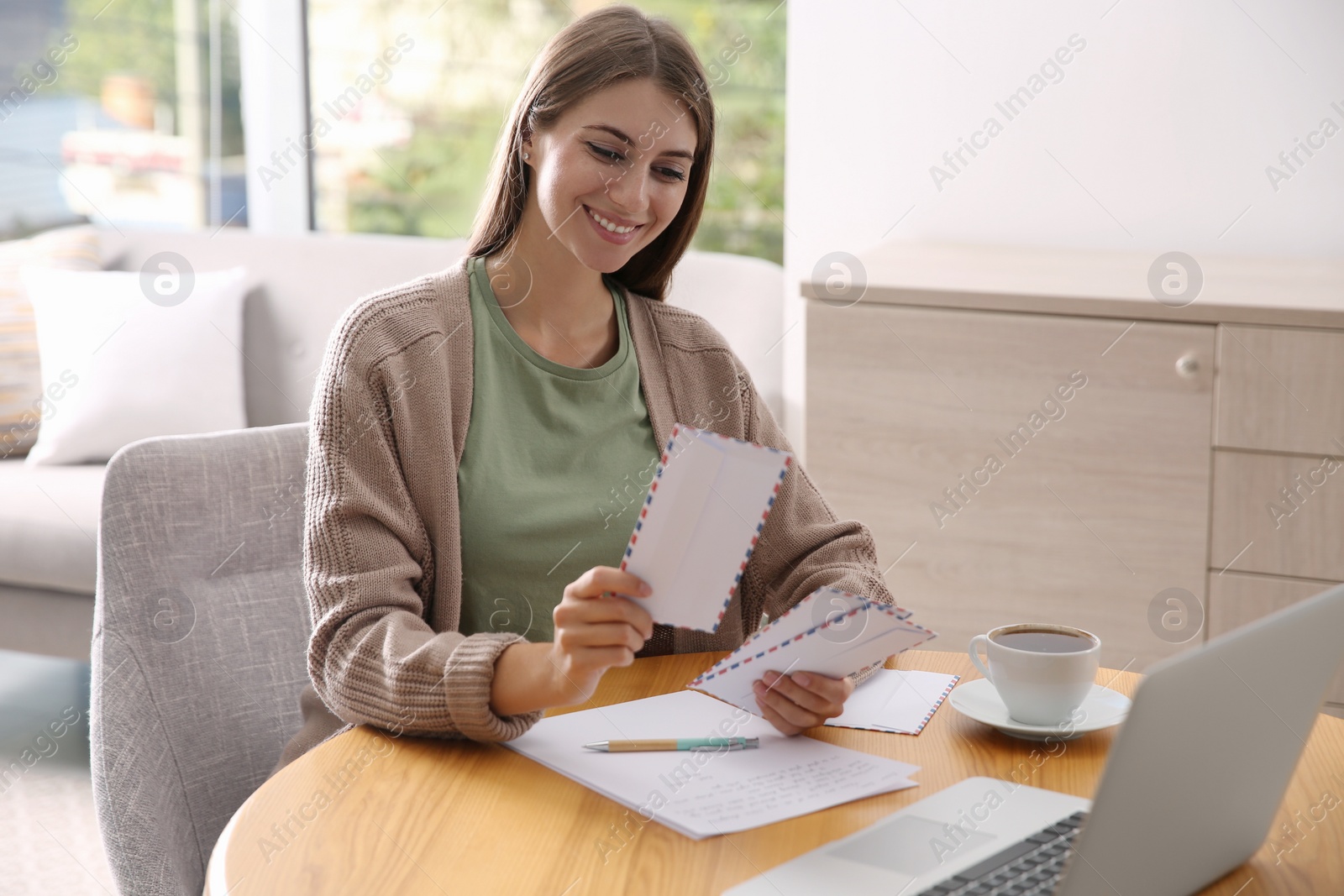 Photo of Woman with letter at wooden table in room