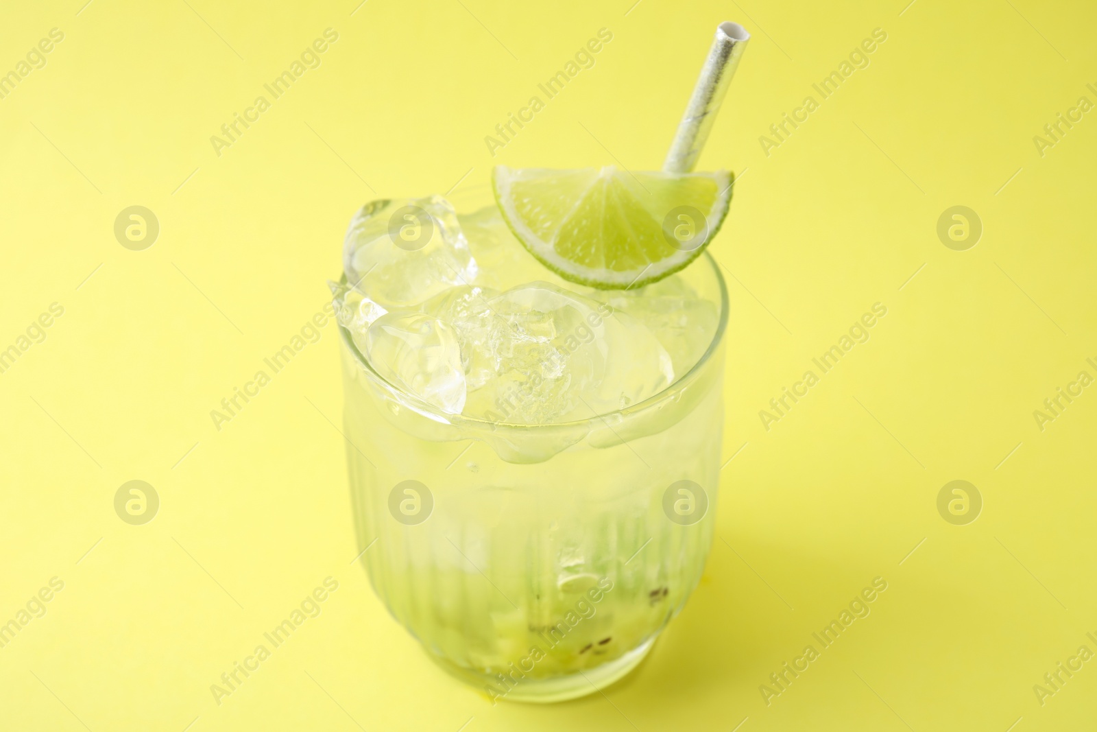 Photo of Glass of refreshing drink with kiwi and lime on yellow background
