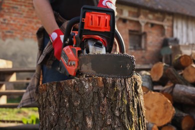 Man sawing wooden log outdoors, closeup view