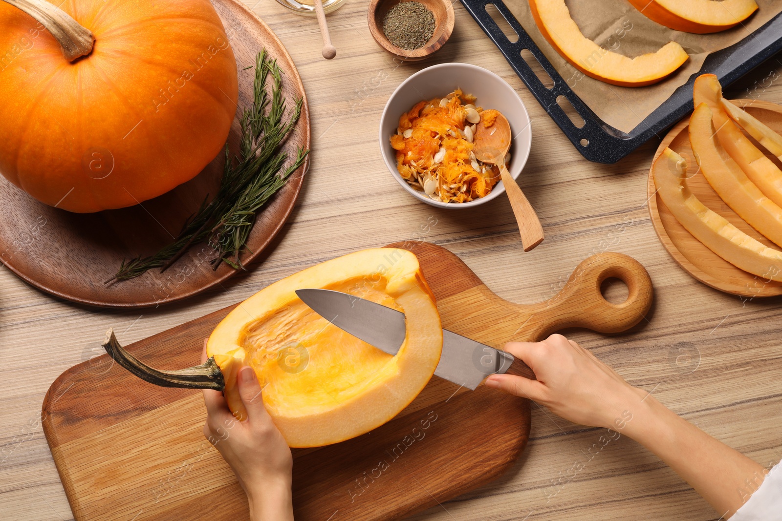 Photo of Woman slicing fresh pumpkin at wooden table, top view