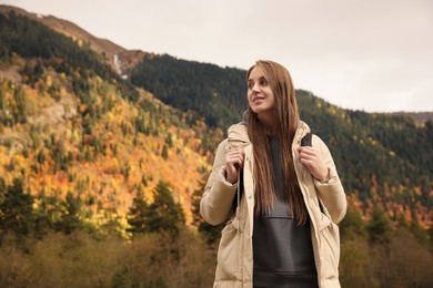 Photo of Happy woman with backpack in beautiful mountains, low angle view. Space for text