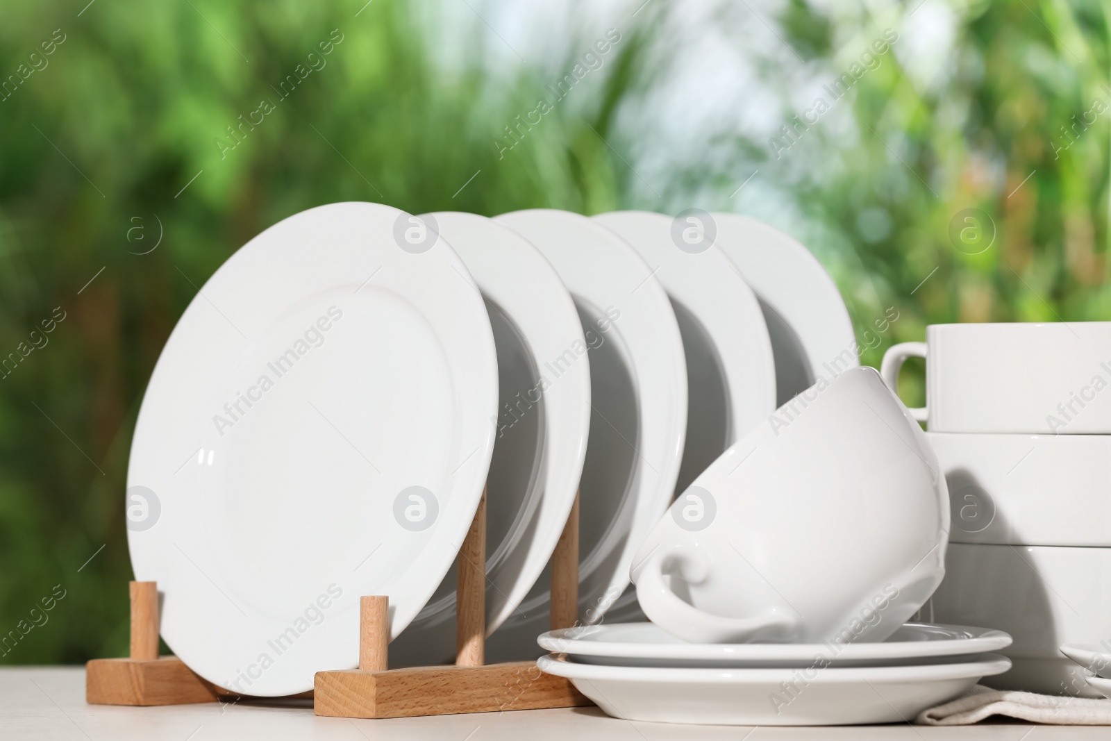 Photo of Set of clean dishware on white table against blurred background