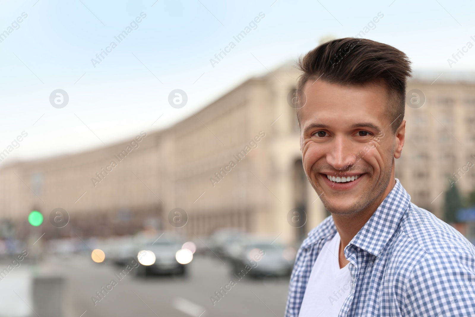 Photo of Portrait of handsome young man on city street. Space for text