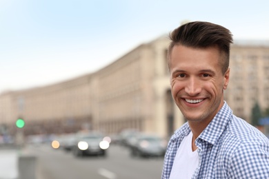 Portrait of handsome young man on city street. Space for text