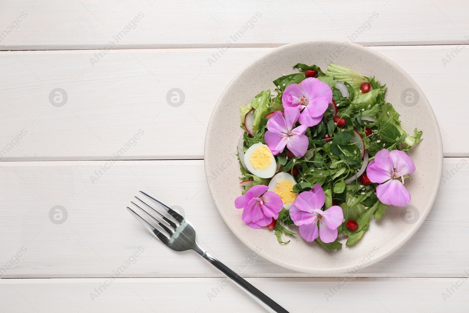 Photo of Fresh spring salad with flowers served on white wooden table, flat lay. Space for text