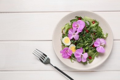 Fresh spring salad with flowers served on white wooden table, flat lay. Space for text