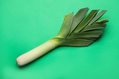 Photo of Fresh raw leek on green background, top view. Ripe onion