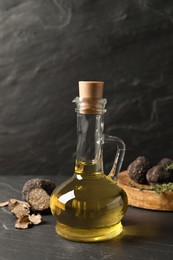 Fresh truffle oil in glass jug on black table