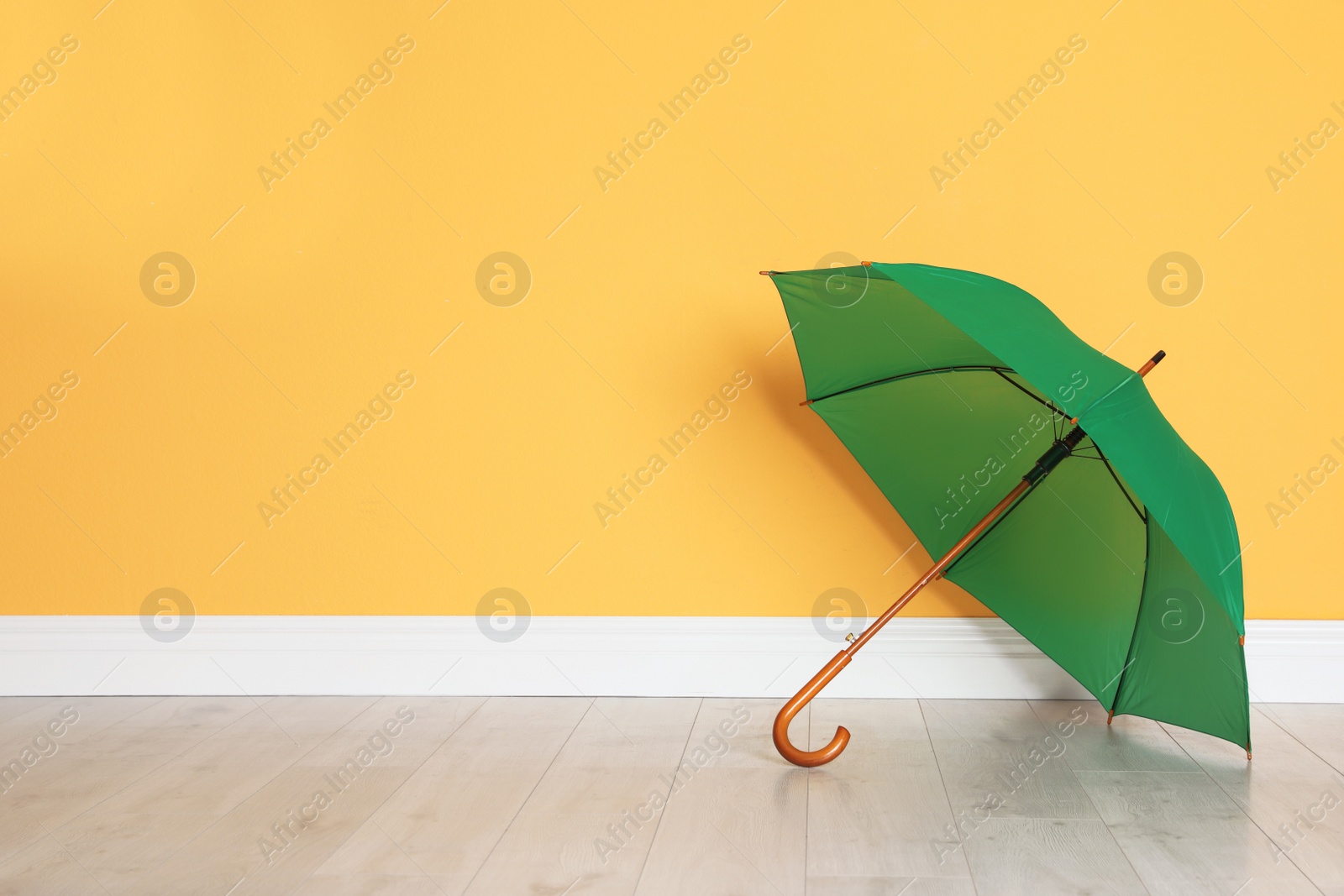 Photo of Beautiful open umbrella on floor near color wall with space for design