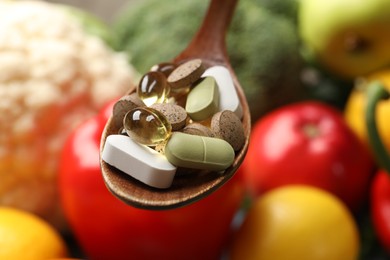 Photo of Dietary supplements. Spoon with different pills over food products, closeup