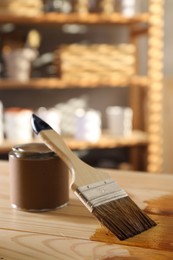 Photo of Brush and can with wood stain on wooden surface indoors