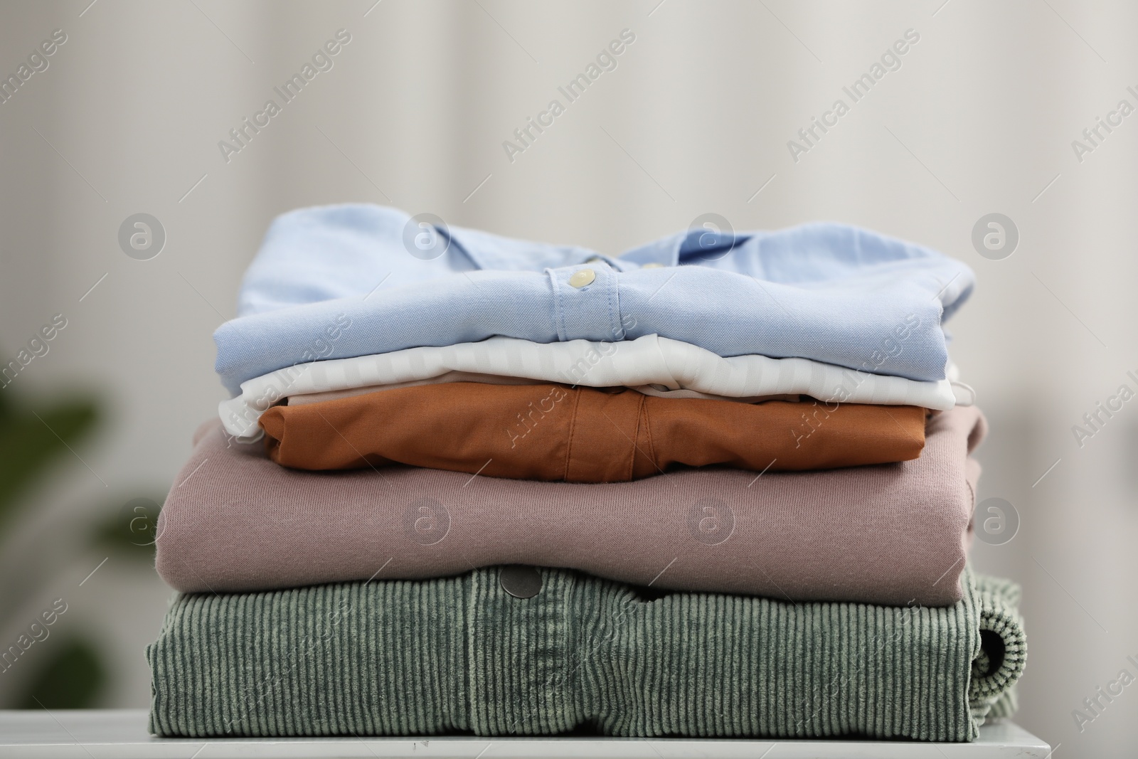 Photo of Stack of different folded clothes white on table, closeup