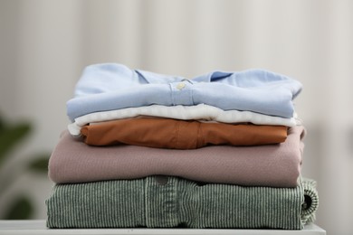 Photo of Stack of different folded clothes white on table, closeup