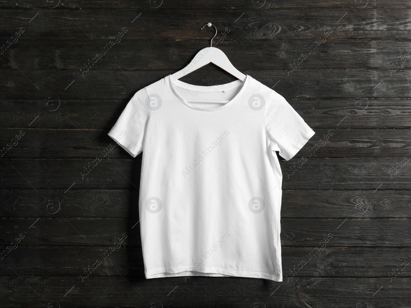 Photo of Hanger with white t-shirt on wooden background. Mockup for design