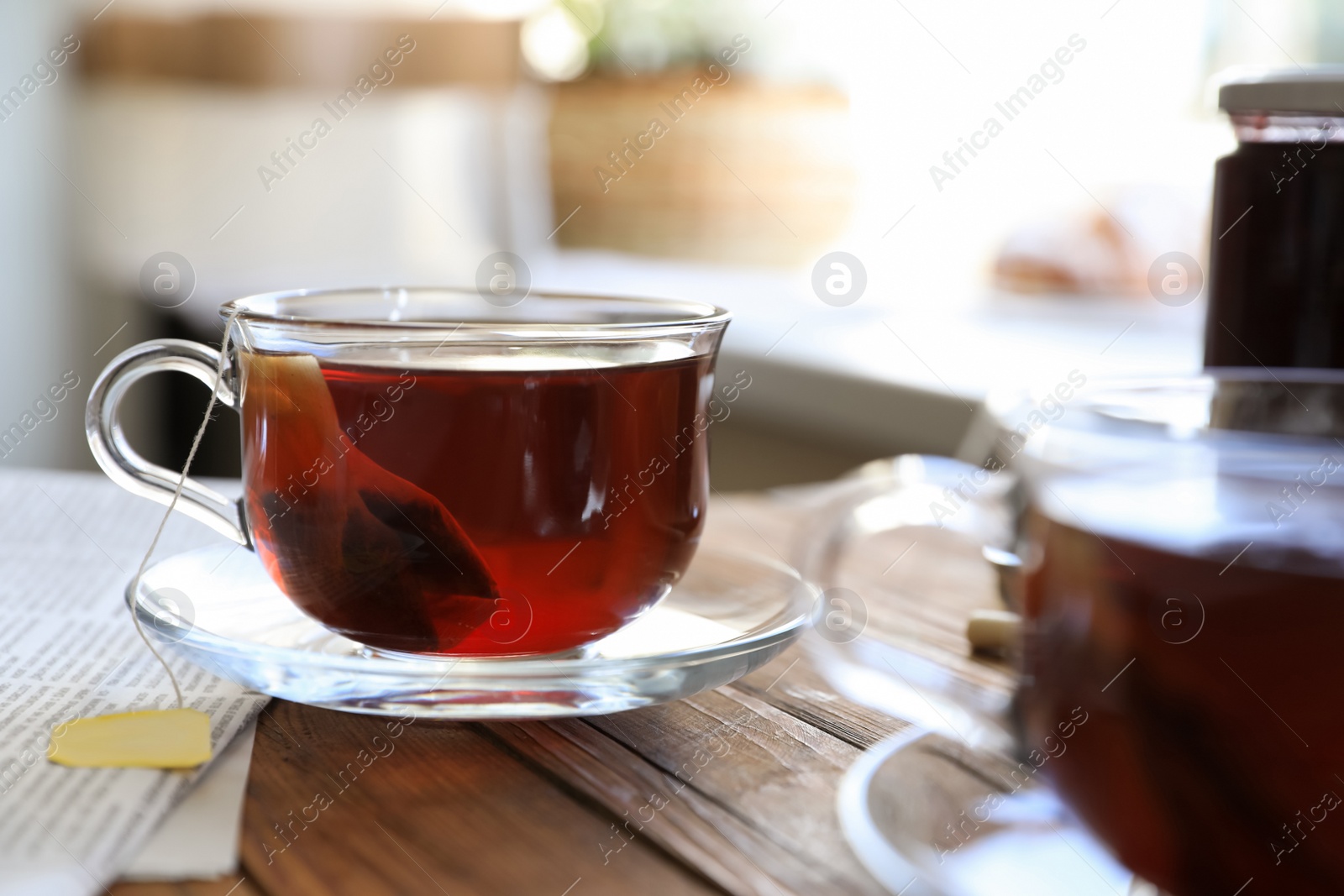 Photo of Tea bag in glass cup on wooden table indoors, closeup