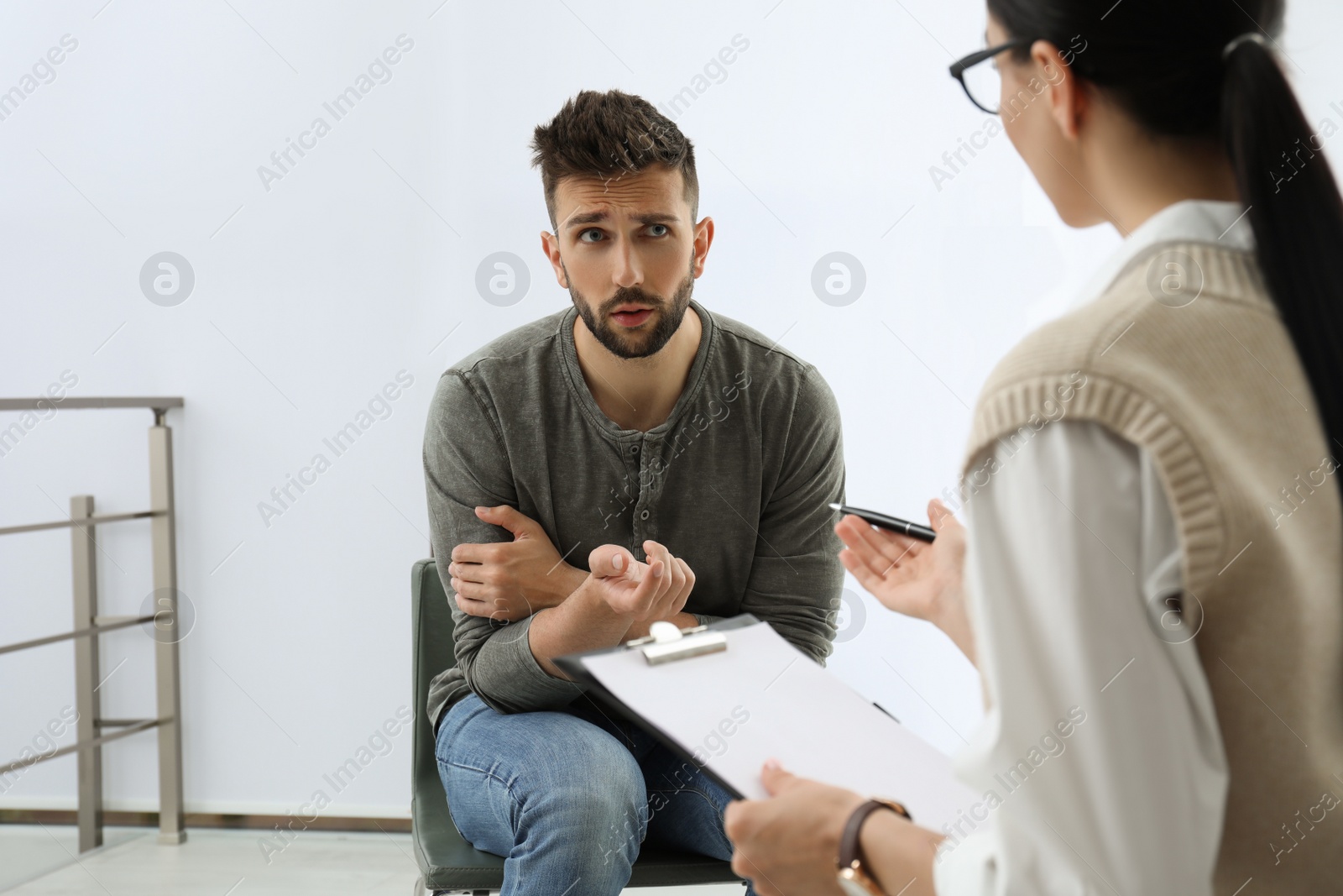 Photo of Psychotherapist working with drug addicted man indoors