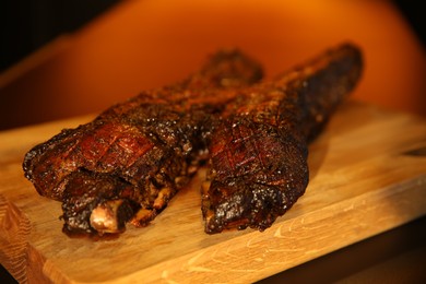 Photo of Tasty grilled pork ribs on wooden board, closeup