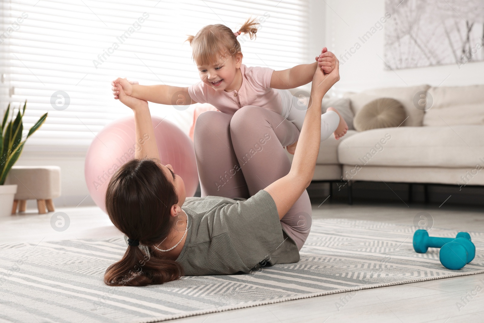 Photo of Mother doing exercise with her daughter at home