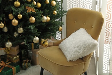 Photo of Beautifully decorated Christmas tree and many gift boxes near armchair in room