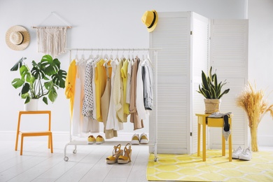 Photo of Dressing room interior with clothing rack and houseplants