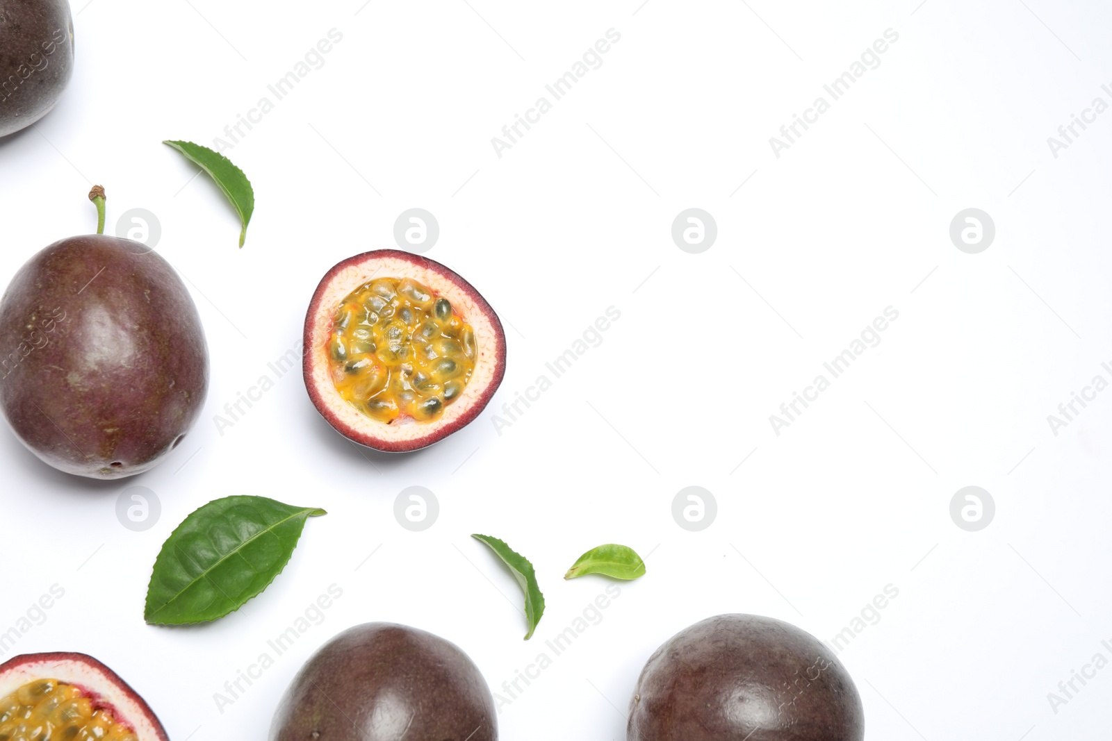 Photo of Fresh ripe passion fruits (maracuyas) with leaves on white background, flat lay. Space for text