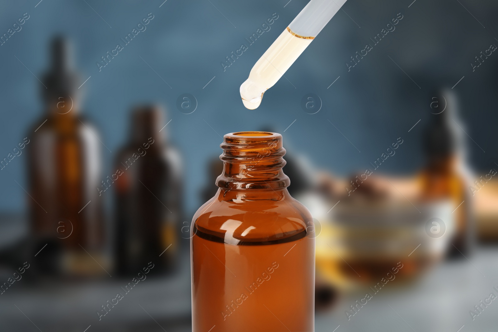 Image of Little bottle with essential oil and dropper against blurred background 