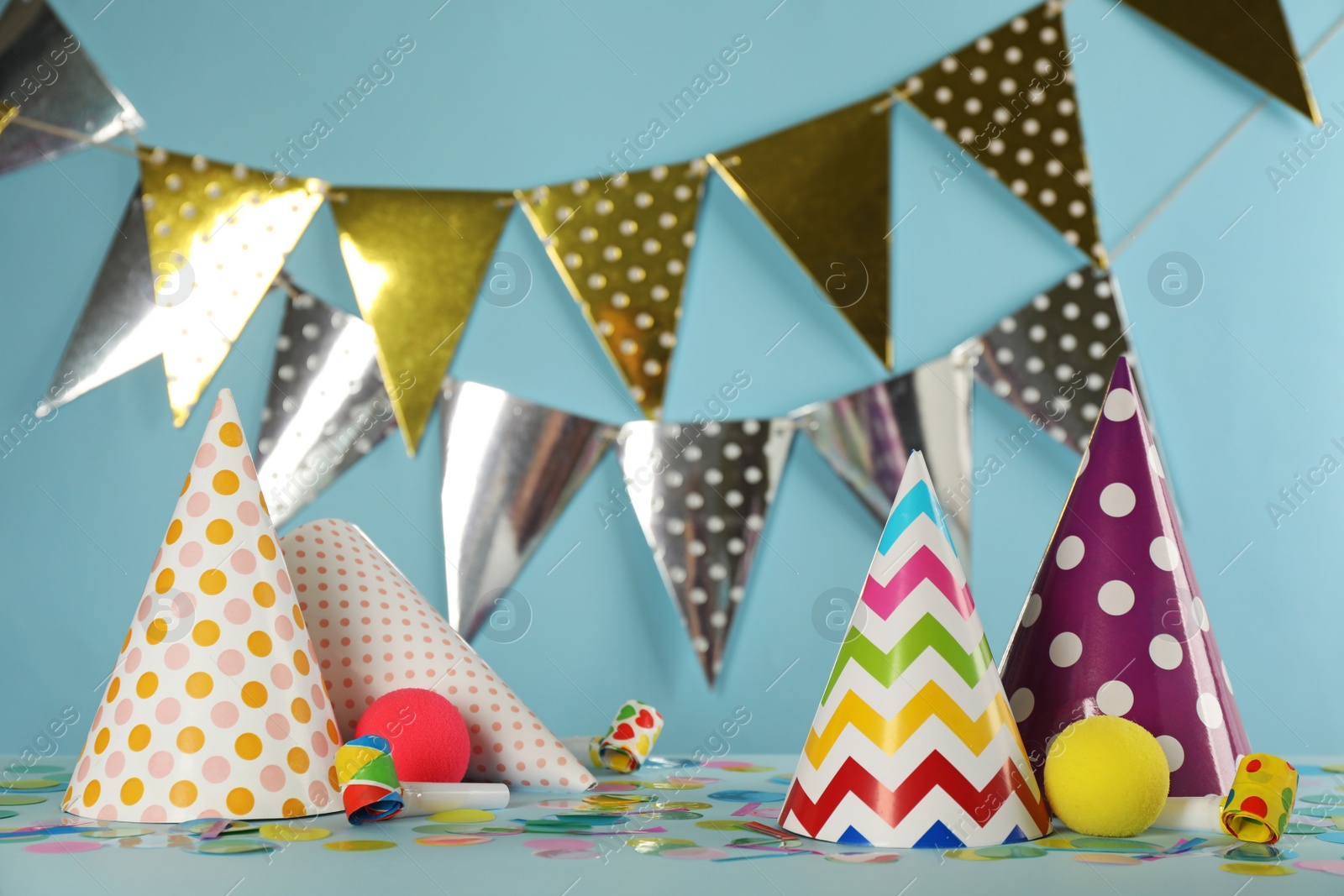 Photo of Colorful party hats and festive items on light blue background