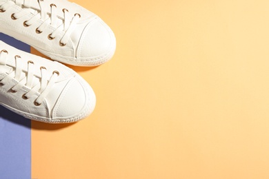 Pair of stylish sneakers on color background, top view with space for text