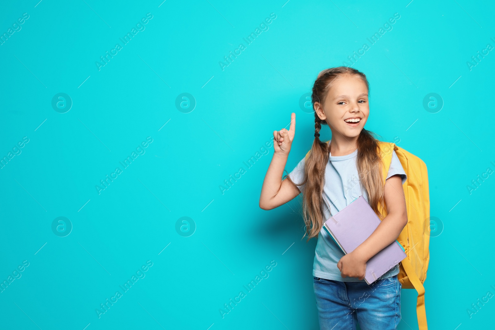 Photo of Little school child with backpack and copybook on color background