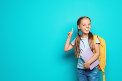 Photo of Little school child with backpack and copybook on color background